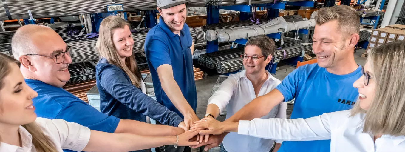 A group of RAMPA employees putting their hands on each other, symbolizing the cohesion of the RAMPA team.