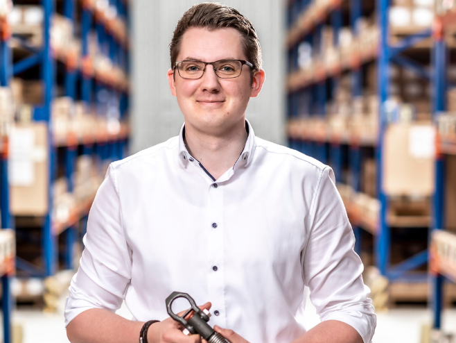 A RAMPA employee representing the Technology Team with a RAMPA product in his hand can be seen, with the warehouse in the background.