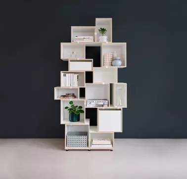 Stocubo is RAMPA's reference partner. A white shelf made of square elements, stylishly arranged on top of each other and offering space for various home items, is placed against a dark background. The shelf was built with the help of RAMPA inserts for a s