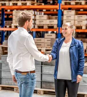 Two RAMPA employees shaking hands in a warehouse in a binding manner.