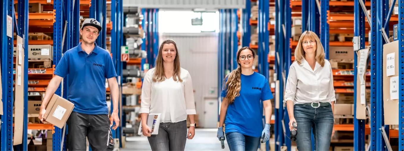 Vier RAMPA-Mitarbeitende gehen nebeneinander durch die Lagerhalle. Sie symbolisieren die verschiedenen, abwechslungsreichen Jobs bei RAMPA.