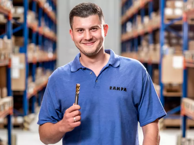 A RAMPA employee representing the Production team with a tool in his hand can be seen, with the warehouse in the background.
