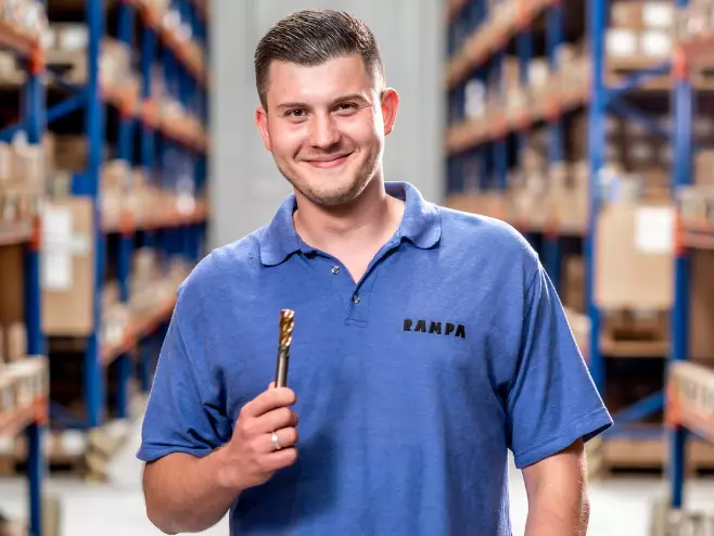 Our teams at RAMPA: Production Department A RAMPA employee representing the Production team with a tool in his hand can be seen, with the warehouse in the background.
