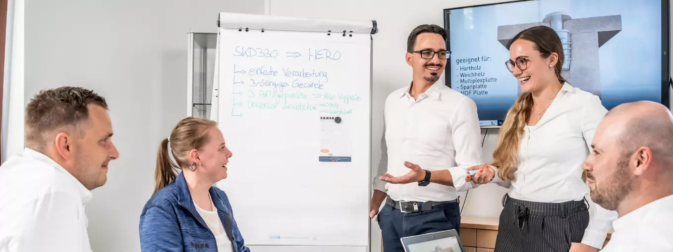 Two people are giving a lecture. The picture is supposed to stand for further education and learning together. It is meant to show that RAMPA always encourages its employees and is happy to support individual development.